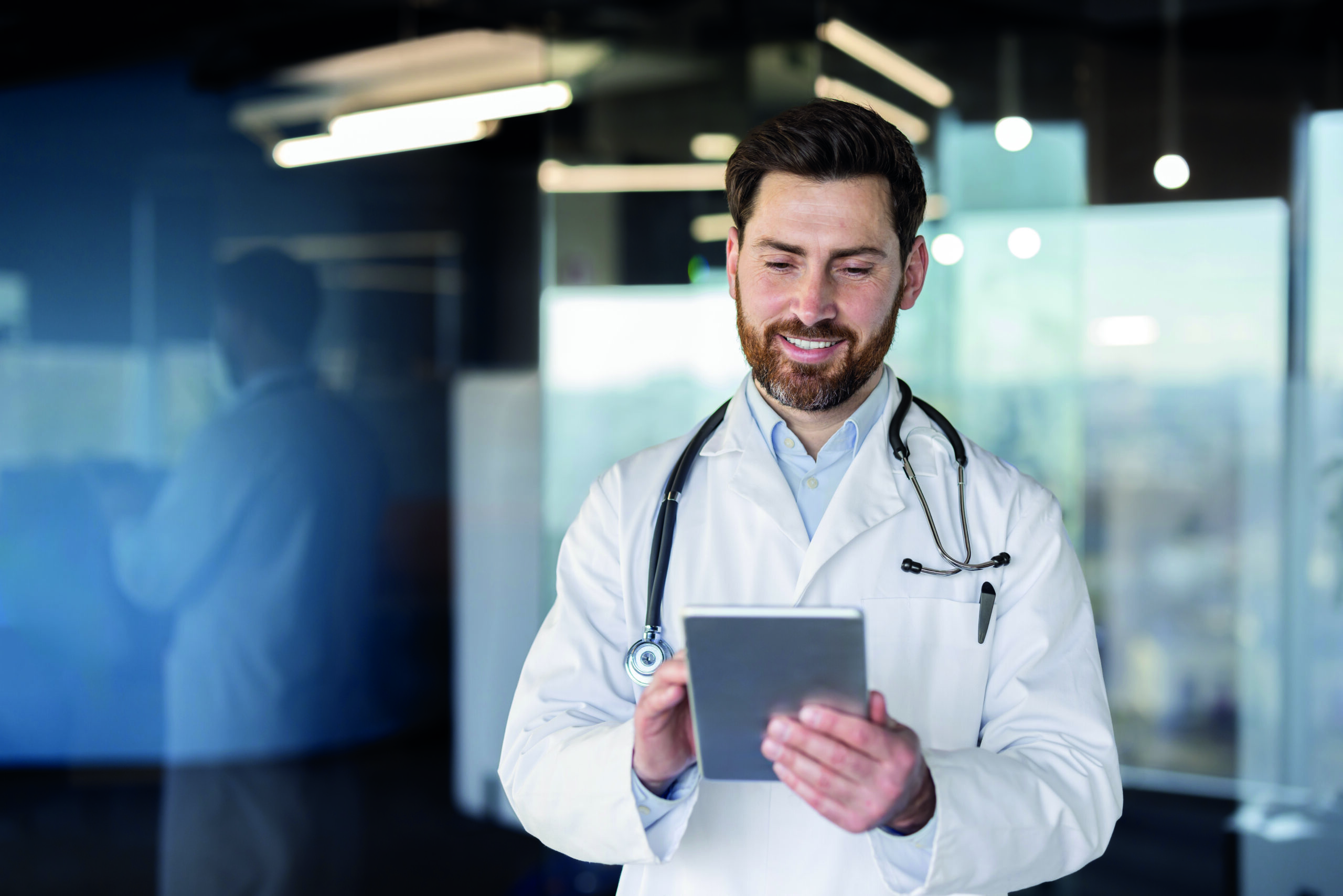 Professional doctor consulting medical information on digital tablet with confidence and smile in modern office. Represents healthcare, technology in medical field, and doctor-patient communication.