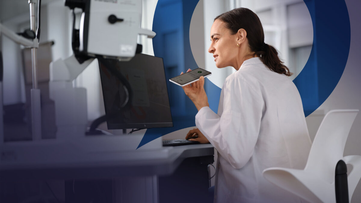 Une médecin en blouse blanche dicte sur son smartphone. En arrière-plan, on aperçoit la bulle bleue Voicepoint et, en bas, le logo Voicepoint.