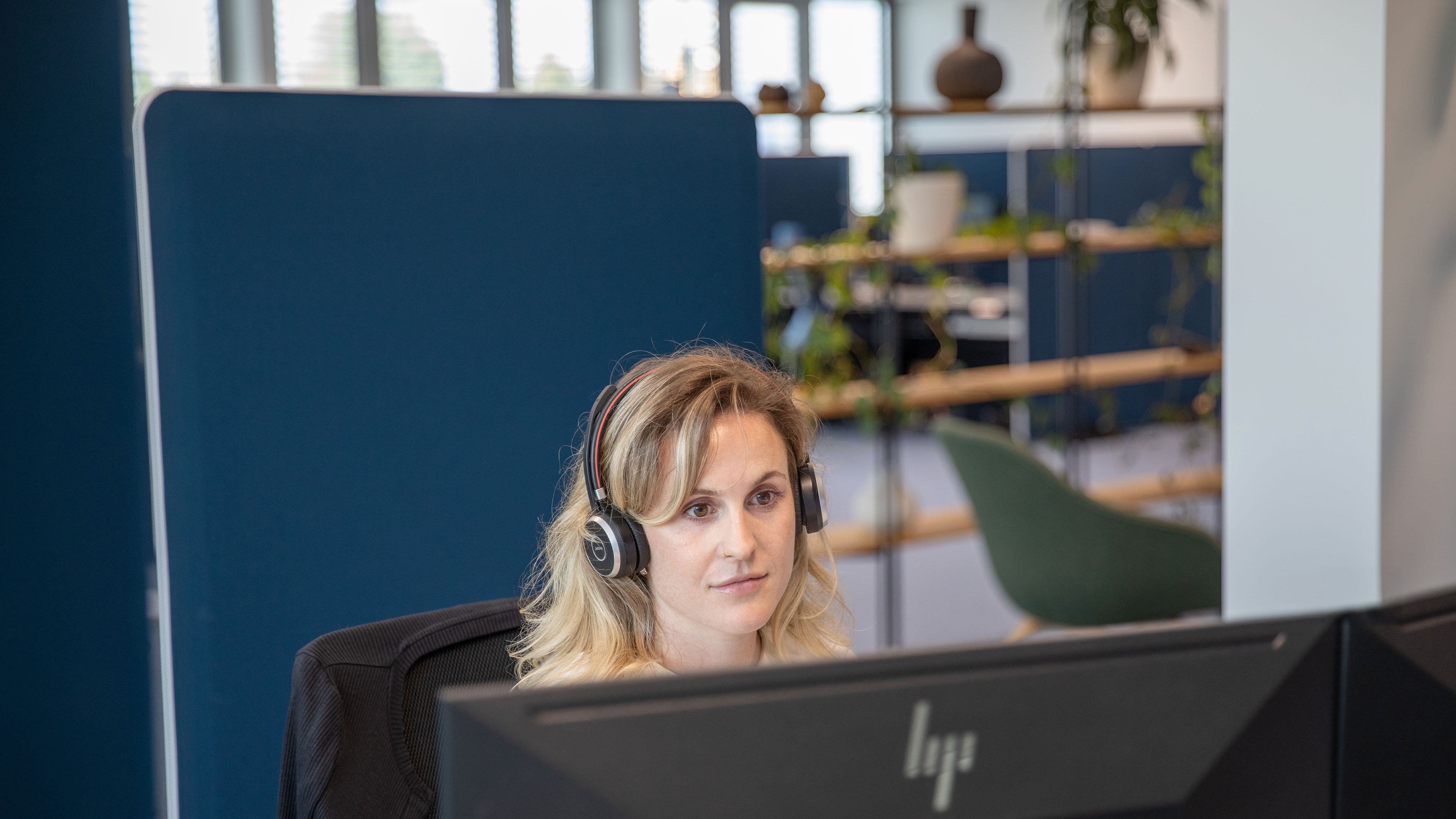 Employee wearing a headset and working intently on a computer.