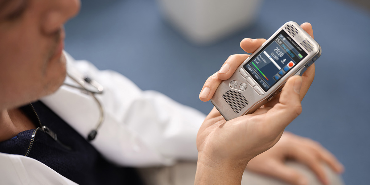 Ein Arzt im weissen Kittel diktiert mit einem Philips Digital Pocket Memo 8000 Diktiergerät