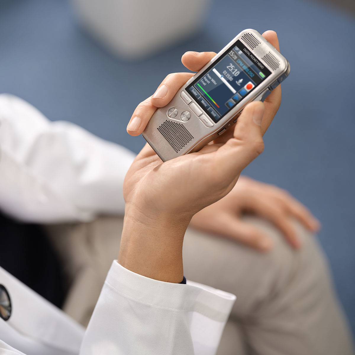 A doctor in a white coat dictates using a Philips Digital Pocket Memo 8000 dictation device.