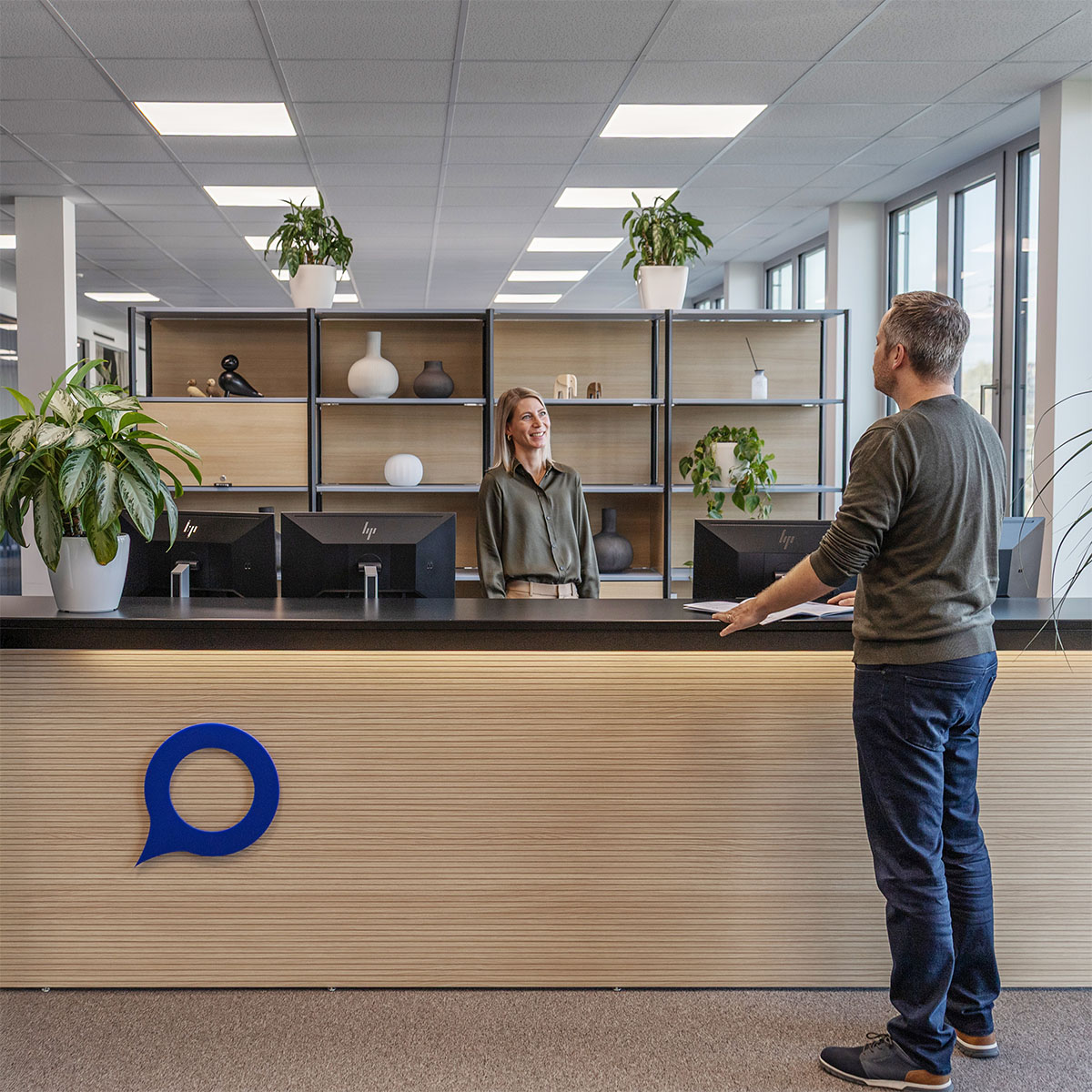 Empfangsbereich der Voicepoint AG mit grosser Fensterfront und zwei Menschen davor, die sich unterhalten.