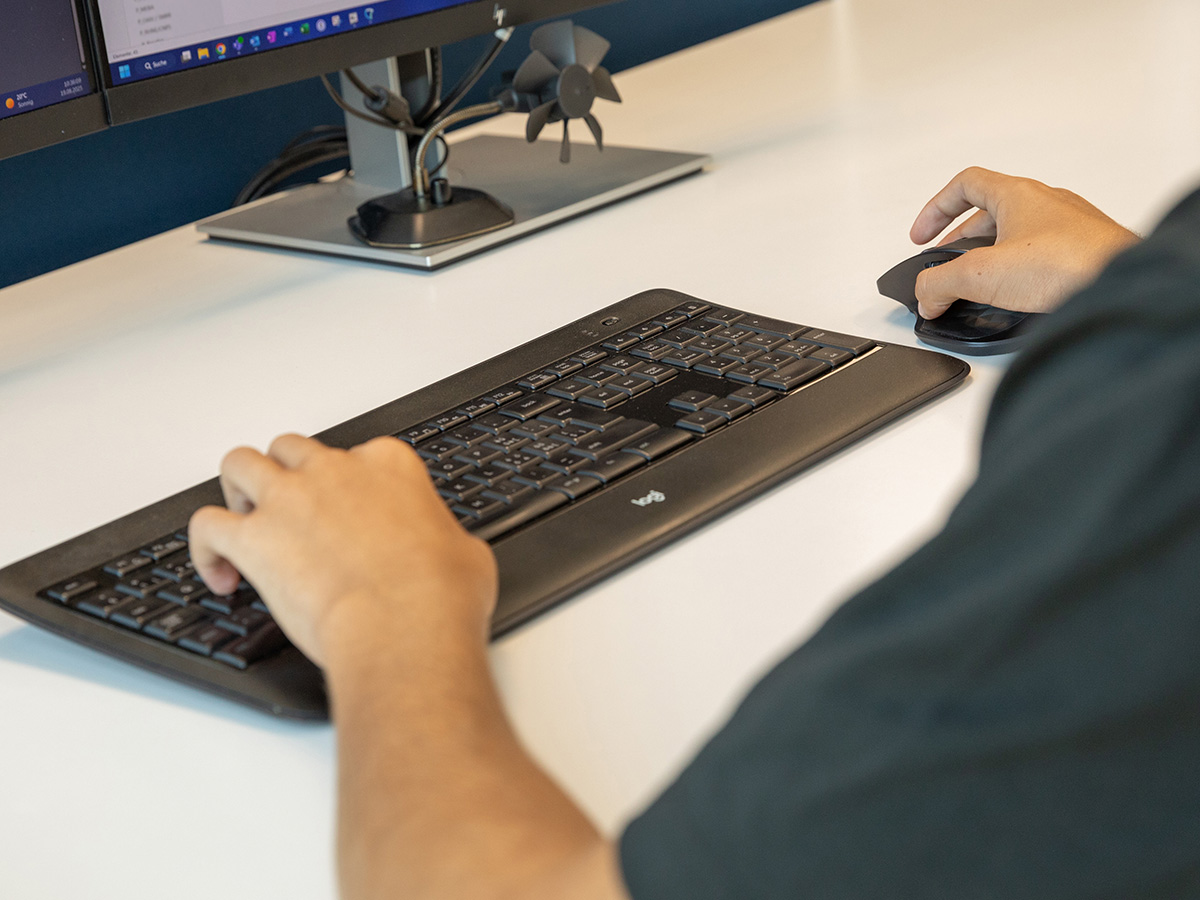 Lernender der Voicepoint AG arbeitet am Computer, die Hände liegen auf der Tastatur und der Maus.