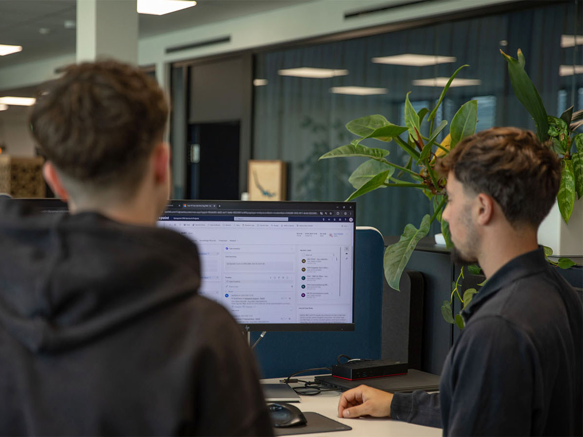 Zwei Lernende der Voicepoint AG stehen vor einem Bildschirm und besprechen ein gemeinsames Projekt.