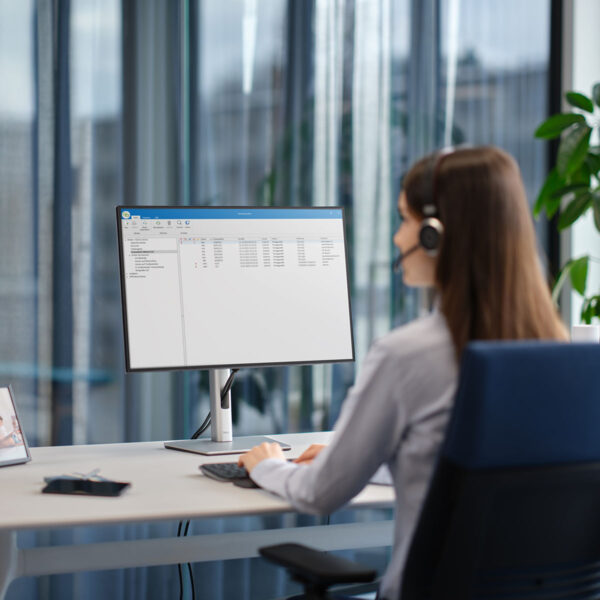 Eine Frau mit Headset sitzt im Büro vor einem Computer und nutzt die Winscribe Diktiersoftware.