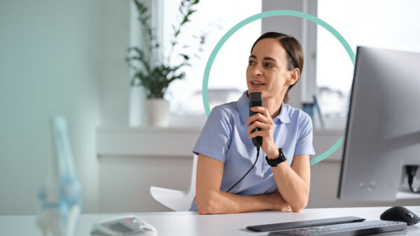 Ärztin sitzt im Sprechzimmer, diktiert mit einem Diktiergerät und nutzt dabei medizinische Spracherkennung. Im Hintergrund ist ein blauer Kreis als Gestaltungselement zu sehen.