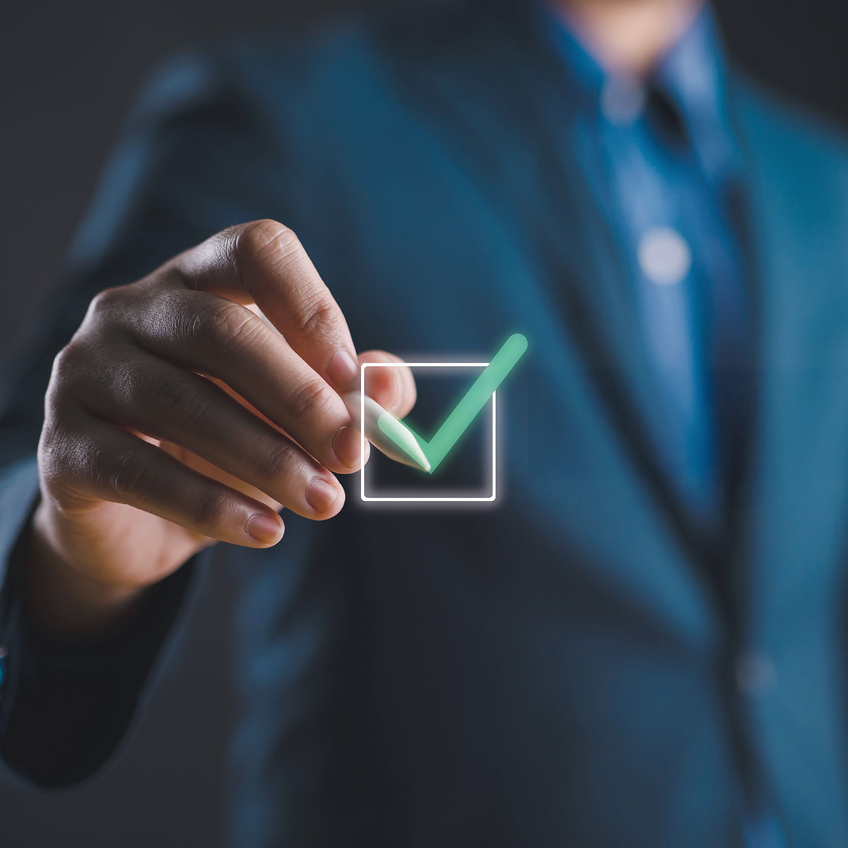 Eine Person im Anzug tippt auf ein digitales Kontrollkästchen mit grünem Haken.