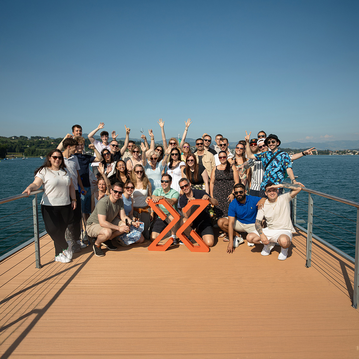 Das Voicepoint-Team befindet sich auf einem Boot, lacht und posiert gemeinsam mit einem grossen orangefarbenen Voicepoint Xenon Logo.