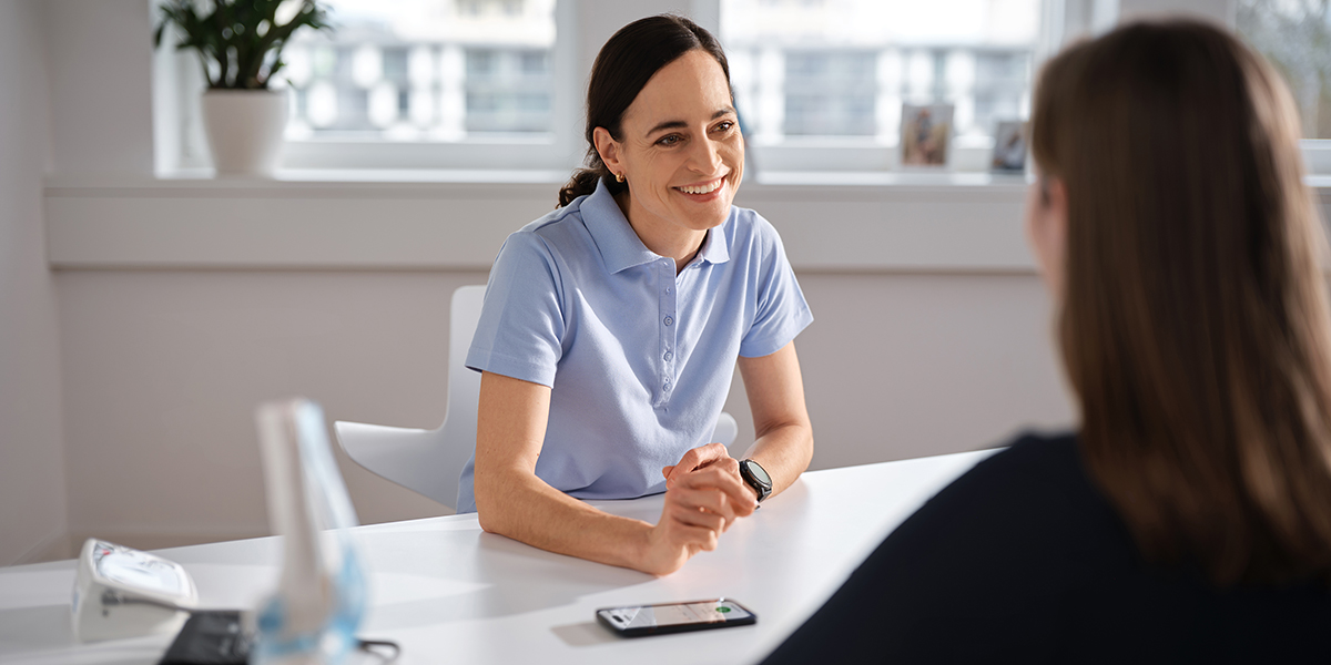 Ärztin und Patientin sitzen im Sprechzimmer sich gegenüber.