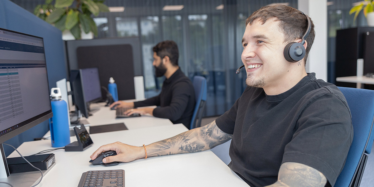 Mitarbeiter mit Headset sitzt am Schreibtisch vor dem Computer und bietet Kundenunterstützung im Rahmen der Services von Voicepoint AG.