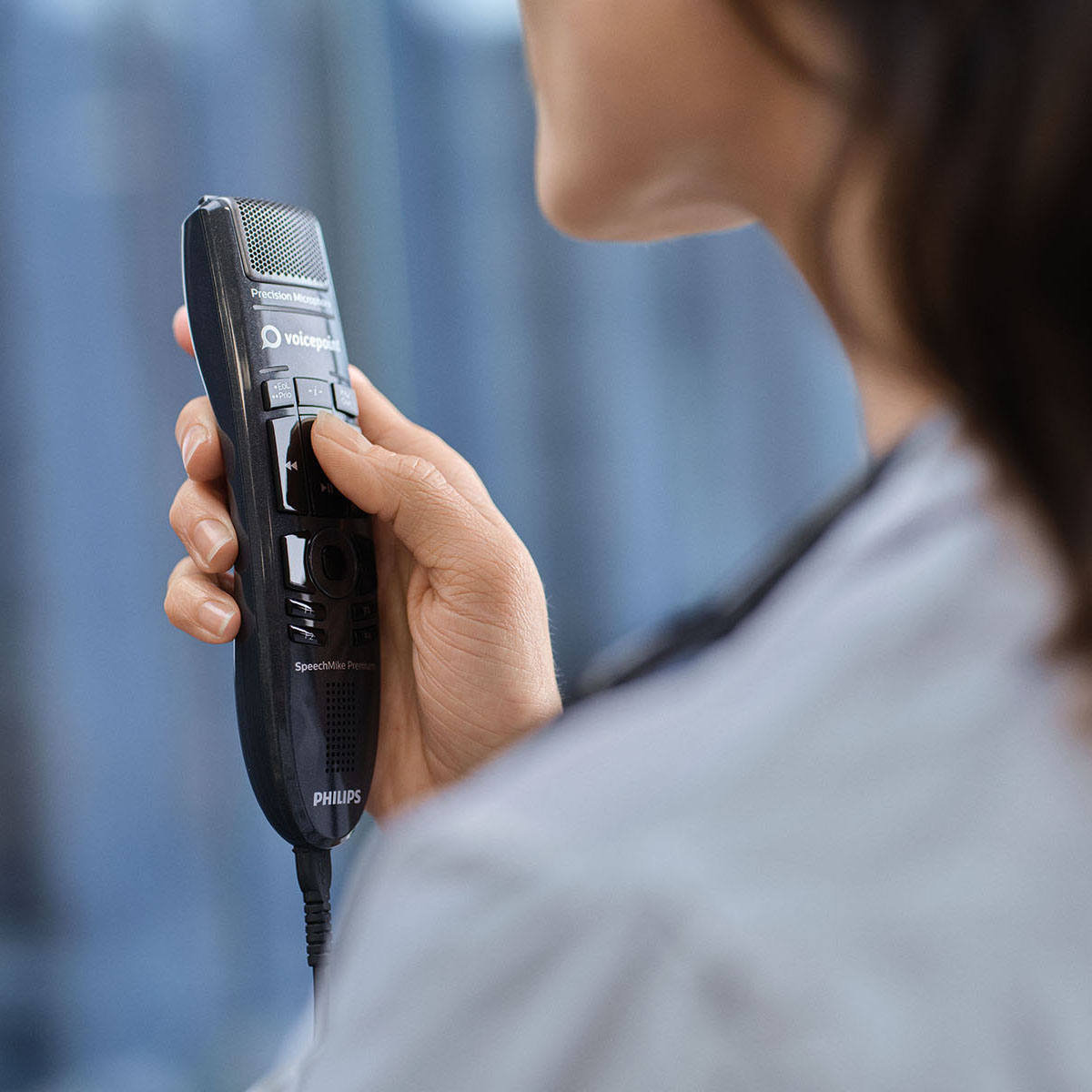 Nahaufnahme einer Ärztin mit Diktiermikrofon, die eine medizinische Spracherkennungssoftware einsetzt.