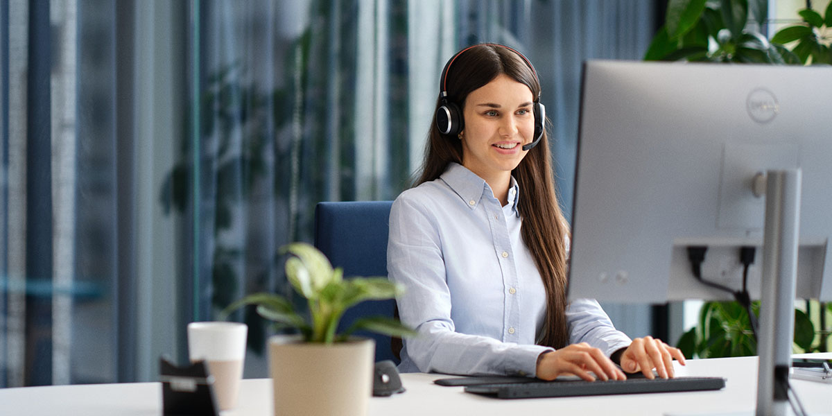 Mitarbeiterin sitzt am Computer, trägt ein Headset und verwaltet Diktate mit der Lösung Voicepoint Xenon Flow.