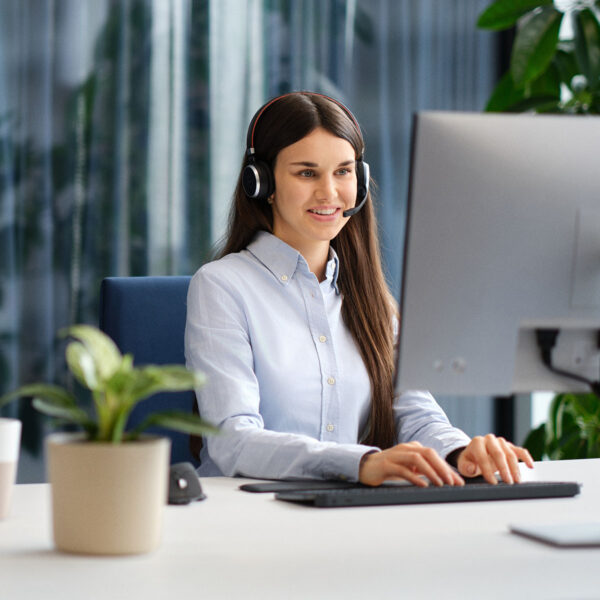 Mitarbeiterin sitzt am Computer, trägt ein Headset und verwaltet Diktate mit der Lösung Voicepoint Xenon Flow.