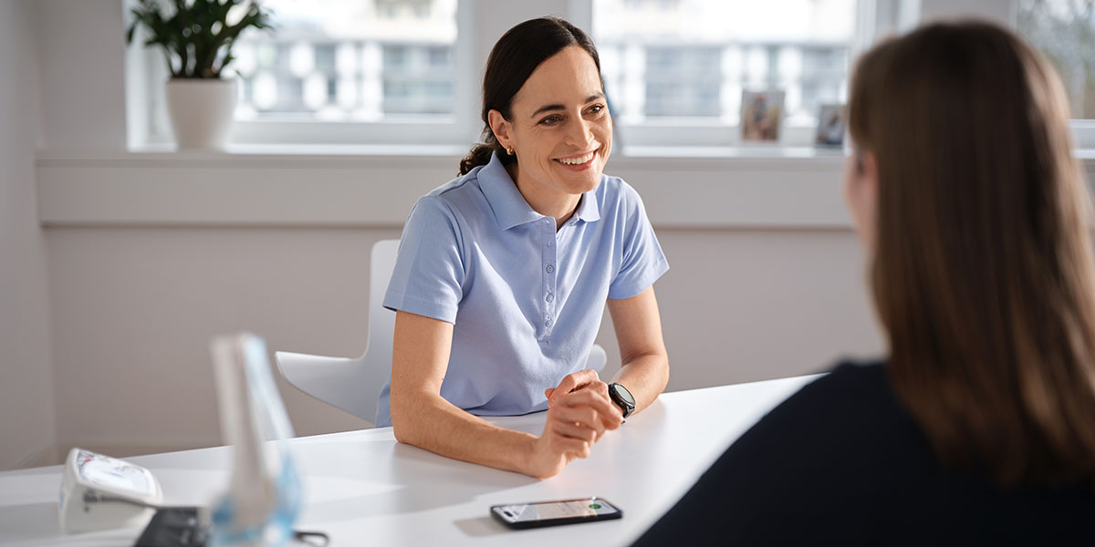 Ärztin sitzt im Sprechzimmer einer Patientin gegenüber und spricht mit ihr, während Voicepoint Xenon Fusion die Sprechstunde automatisch dokumentiert.