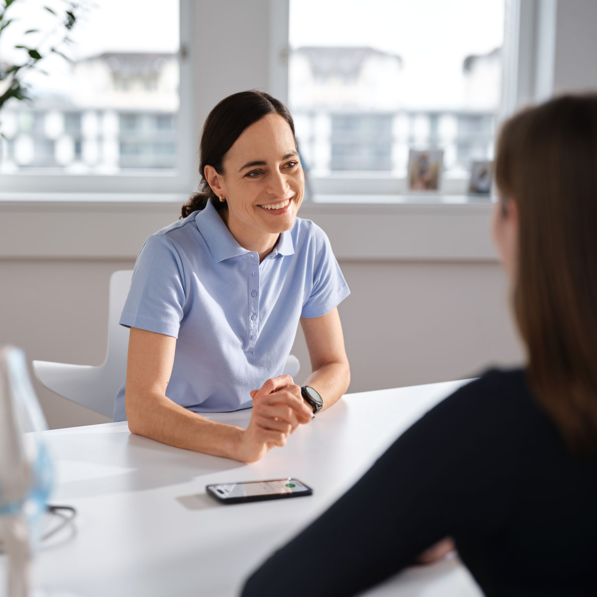 Ärztin sitzt im Sprechzimmer einer Patientin gegenüber und spricht mit ihr, während Voicepoint Xenon Fusion die Sprechstunde automatisch dokumentiert.