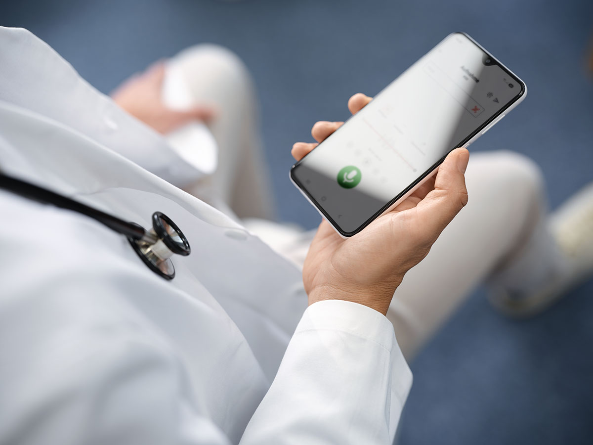 Arzt diktiert mit Smartphone, Symbolbild für die massgeschneiderten Spracherkennungslösungen von Voicepoint.