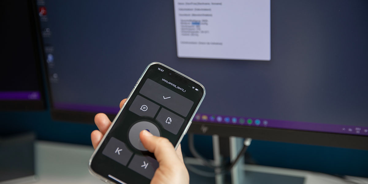 Eine Person sitzt vor dem Computer und diktiert mit der PowerMic Mobile App auf dem Smartphone.